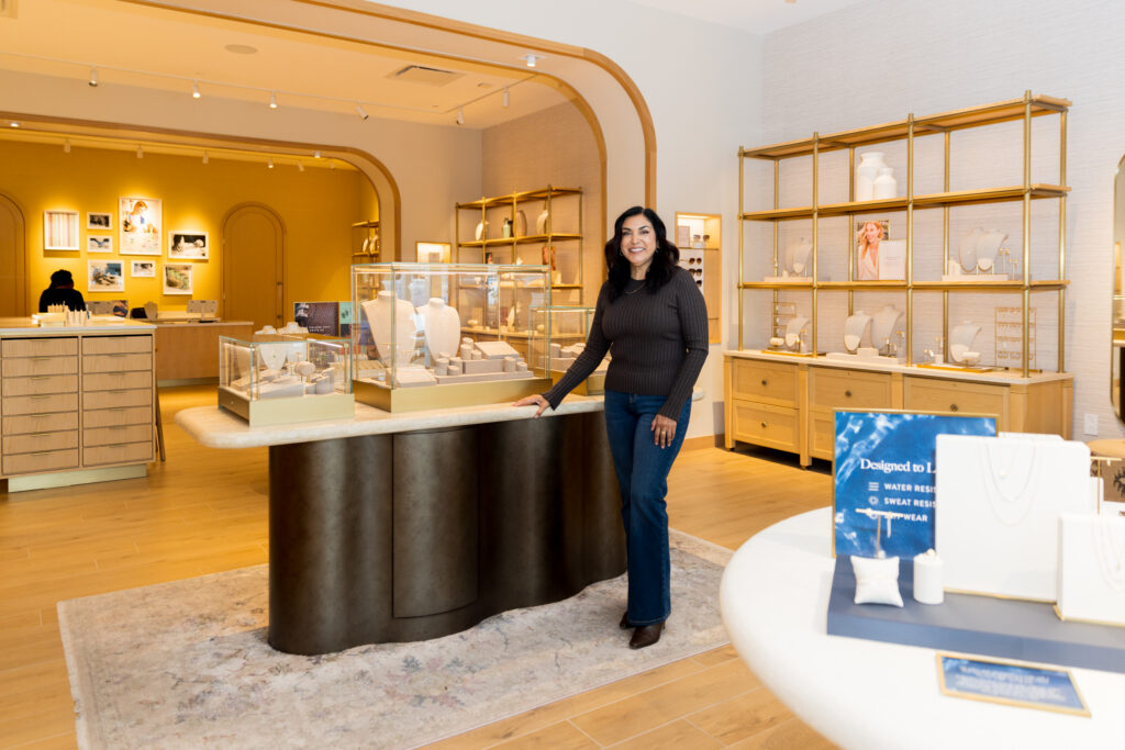 A woman standing in a jewelry store next to a display case filled with necklaces.